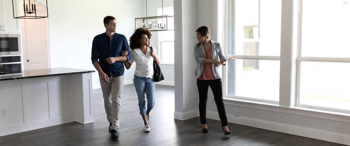 photo of real estate agent giving a tour of a home to a couple